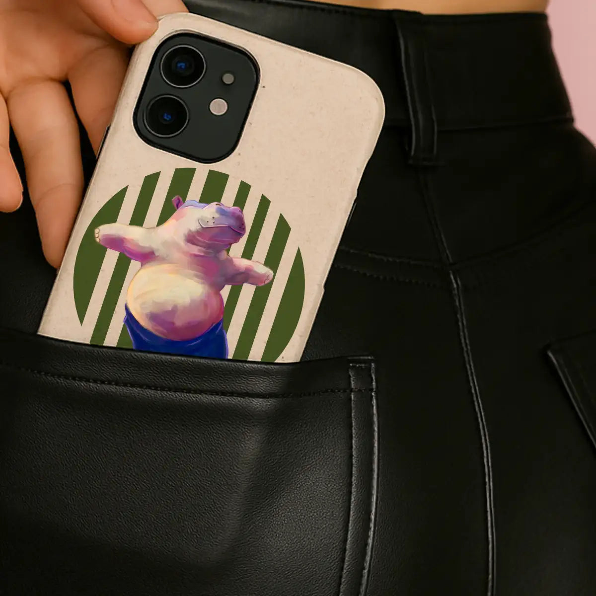 Yoga hippo phone case peeking from back pocket of black faux leather jeans — illustrated eco iPhone case with playful, mindful design.