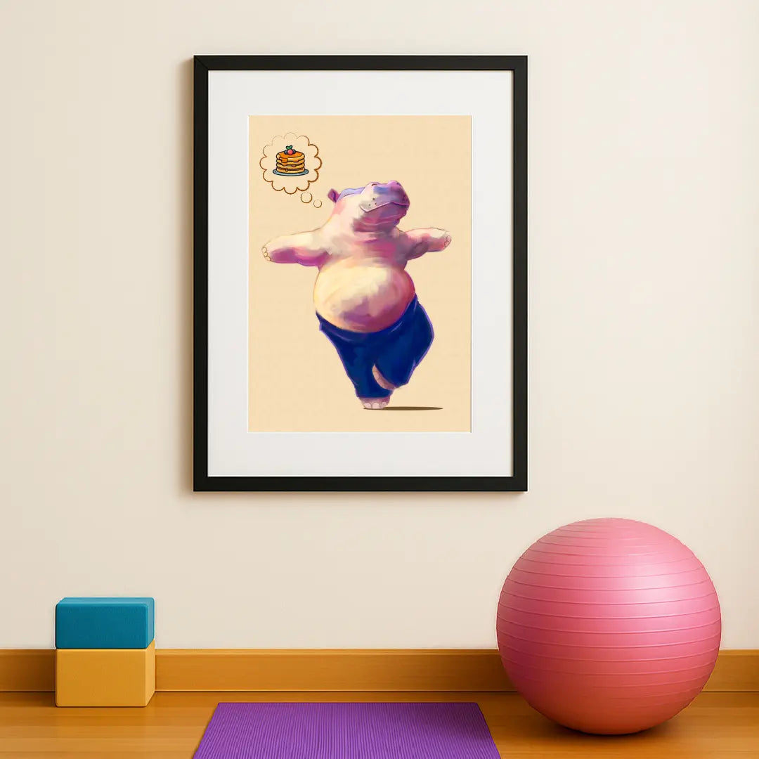 Hippo Yoga Tree Pose Print in black frame, showcased in a full view of a home yoga studio with visible yoga equipment — playful, handmade art for calm, joyful spaces. This quirky illustration is of a happy pink hippo doing their favourite yoga pose (tree pose) while thinking positive thoughts of pancakes for breakfast.