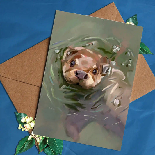 Handmade greeting card featuring a charming illustration of a playful otter in its natural habitat.