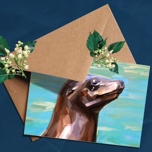 Handmade eco-friendly greeting card featuring a surf-loving seal illustration, printed on sustainable paper with a blank inside.