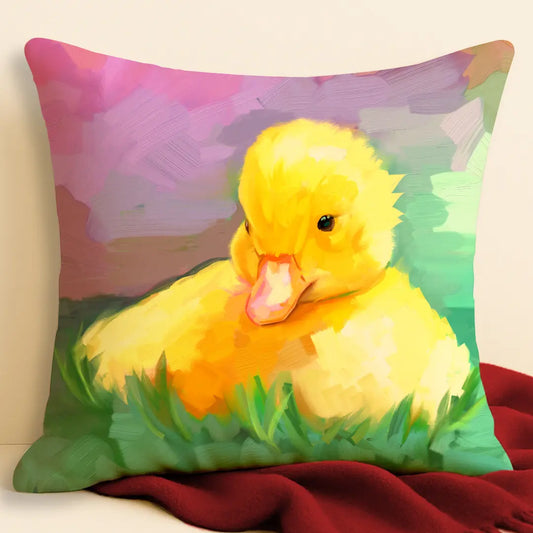 Duckling illustration cushion in bright faux suede, propped against a soft cream wall and red throw — a cosy, colourful home accessory.